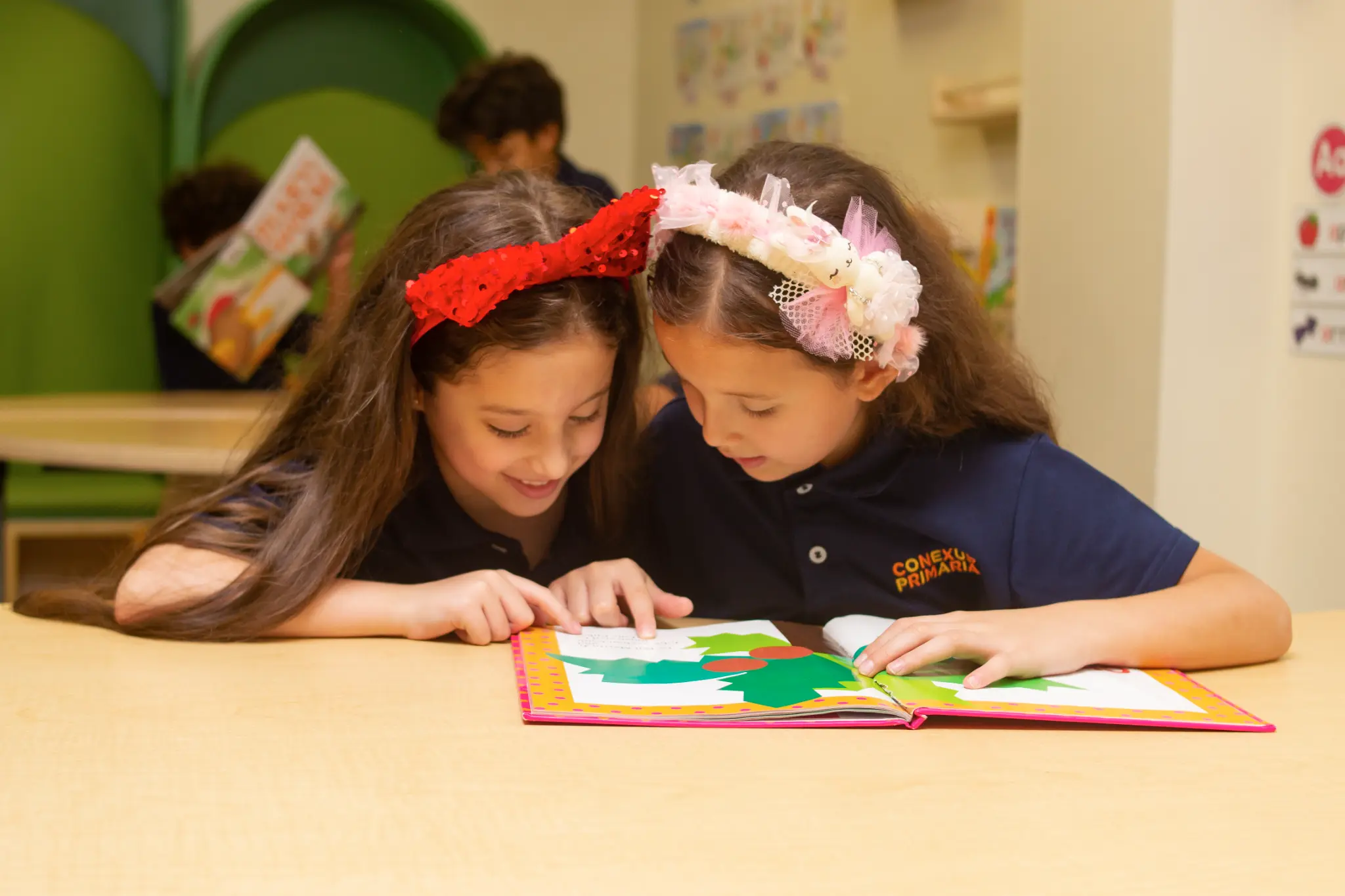 Niñas de primaria leyendo y aprendiendo colaborativamente